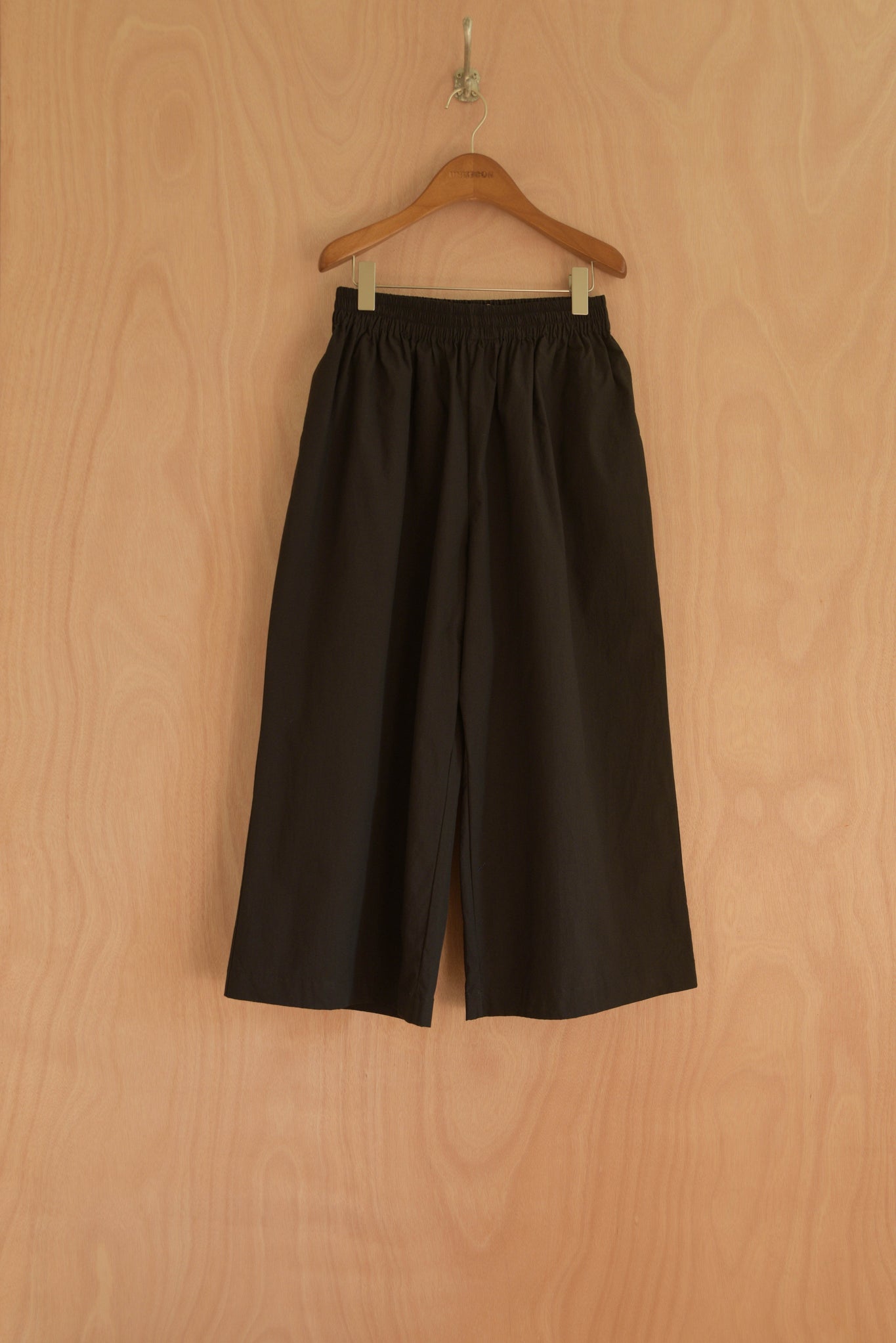 Front view of the Afra Pants in black, wide-leg with an elastic waistband.