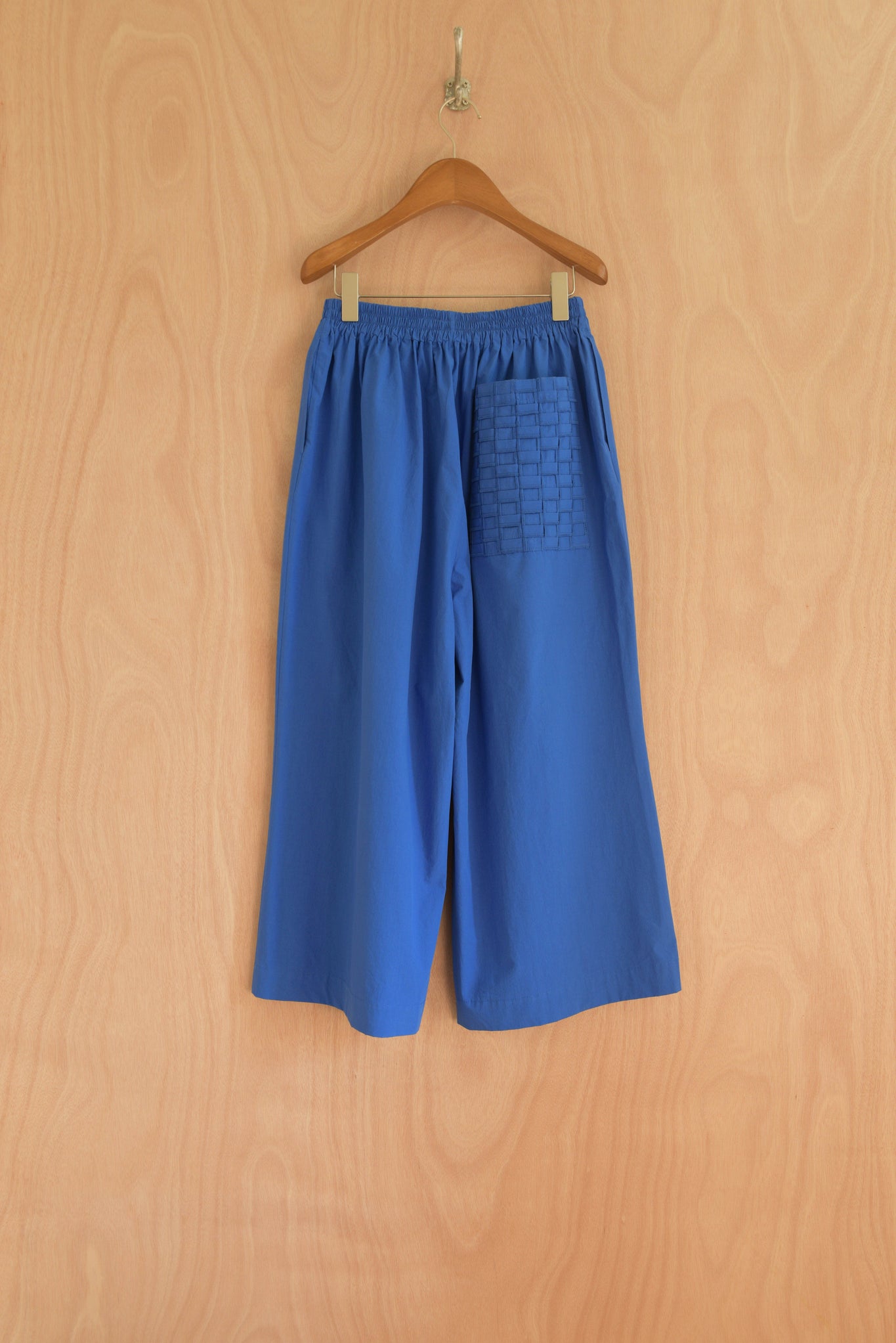 Back view of Afra Pants in blue, highlighting the handwoven pocket detail.