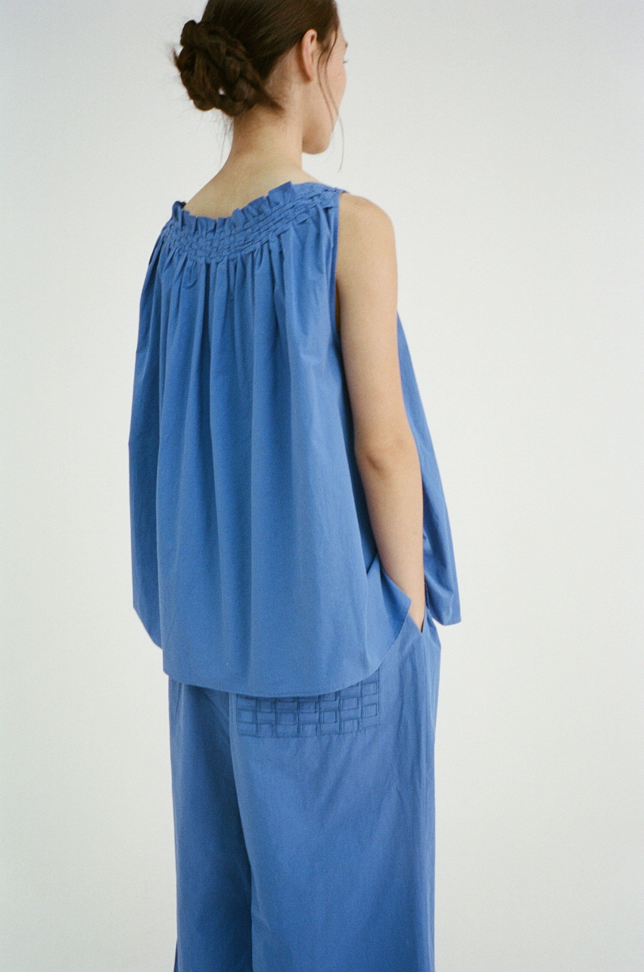 Model wearing Afra Pants in blue, paired with the Olga Top, showing movement and drape.