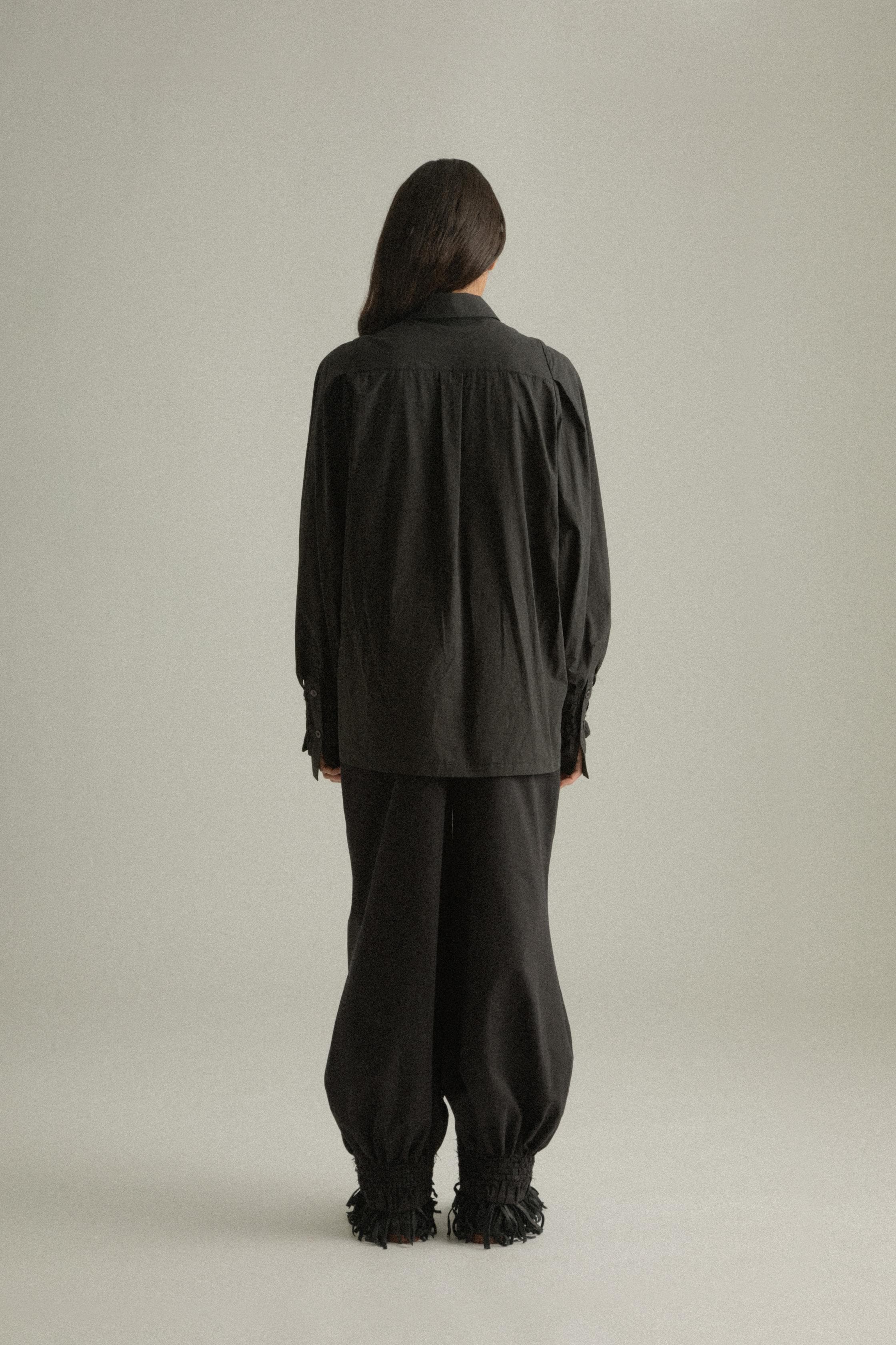 A model wearing the Elias Top, crafted from 100% organic cotton, featuring handwoven sleeves and intricate hand-knit cuffs. Paired with the Qira Pants for a cohesive look. The model is shown in front, side, and back views to highlight the top’s relaxed fit and natural texture.