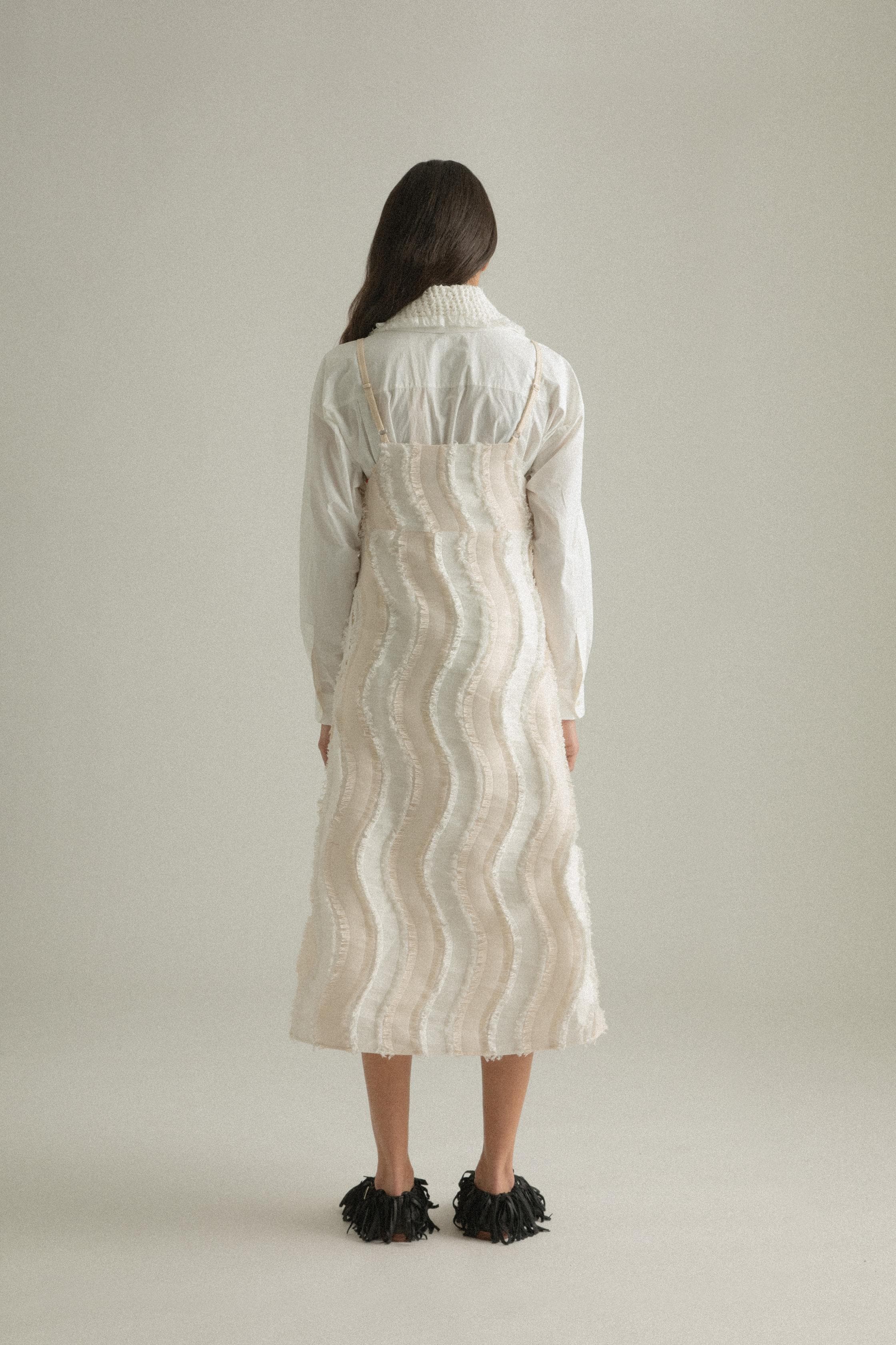 A model wearing the Lena Dress, featuring a wave-like patchwork design made from a blend of cotton, acrylic, and polyester. The model is shown in front, side, and back views to highlight the dress’s texture and A-line silhouette.