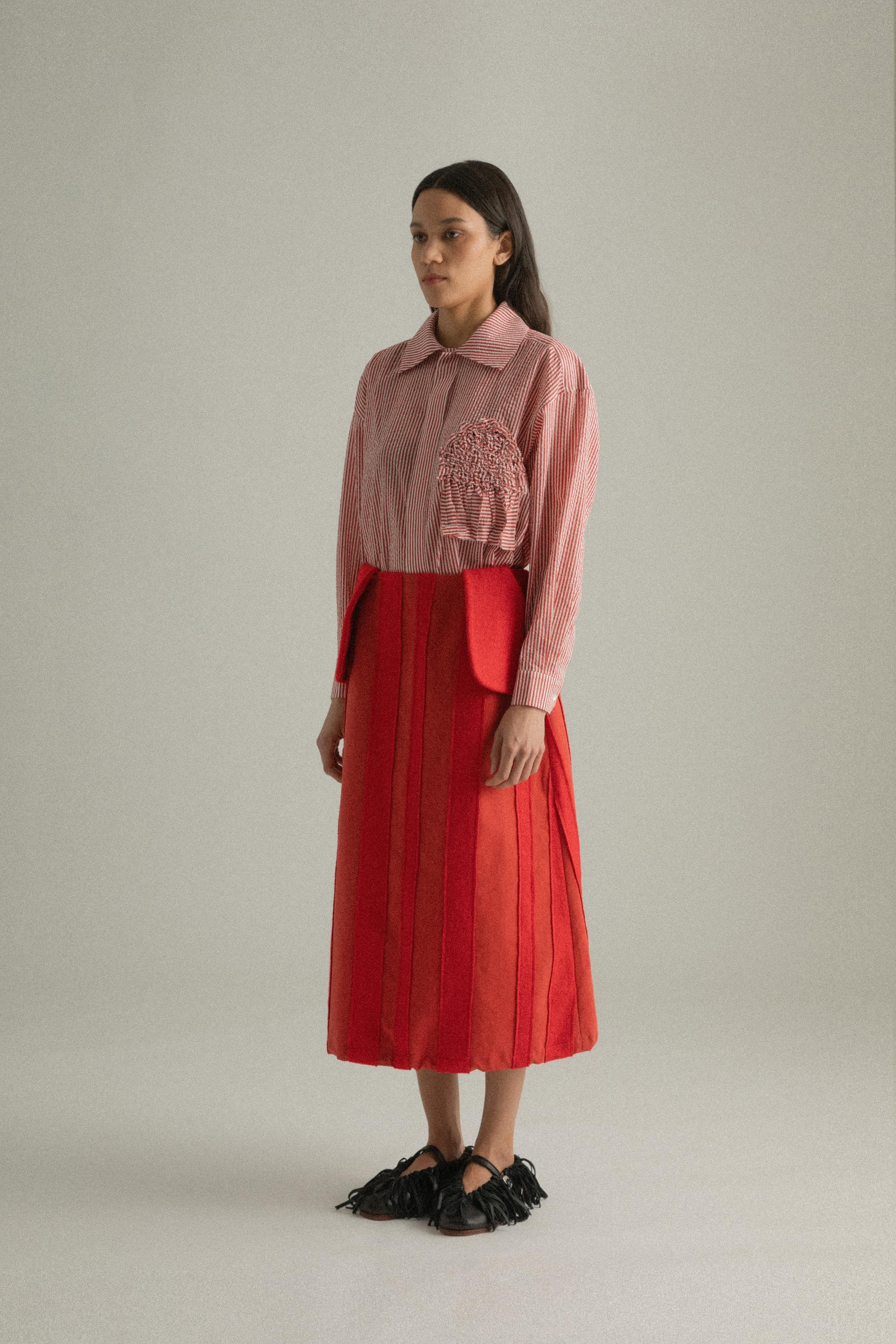 A model wearing the Lulu Skirt in a classic A-line silhouette, crafted from 100% bony cotton with a unique patchwork design. The skirt is styled with the Charlotte Shirt, presenting a layered and colorful look. The model is shown in front, side, and back views.