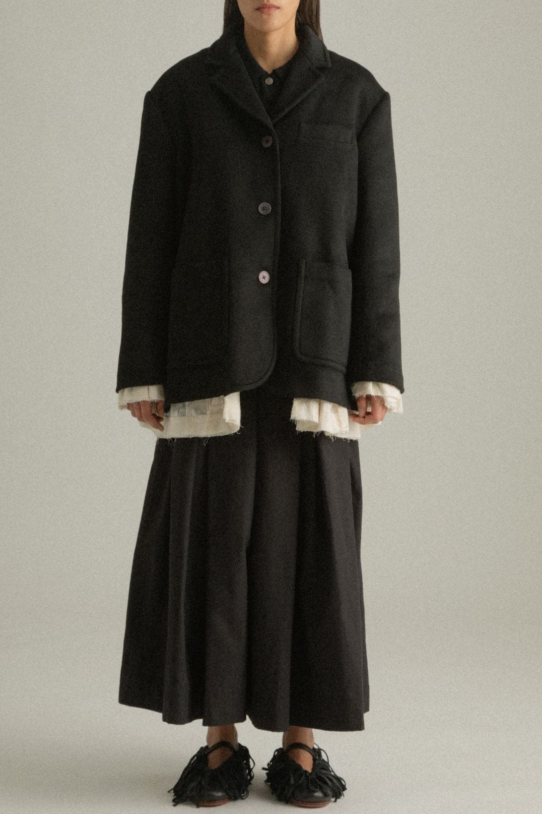 Cropped front view of the Martha Coat’s black wool side, highlighting the lapels and structured fit.