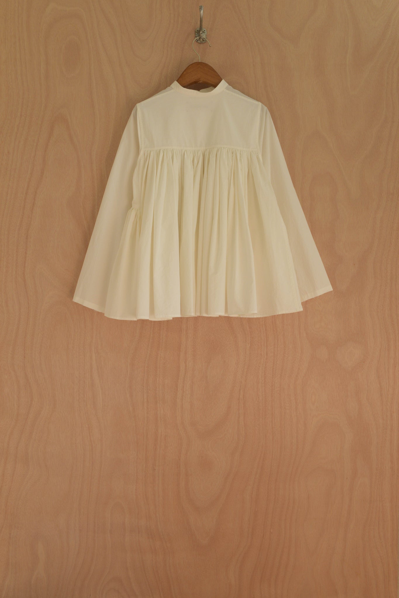 Myra Top back view showing pleated back panel and flared hem