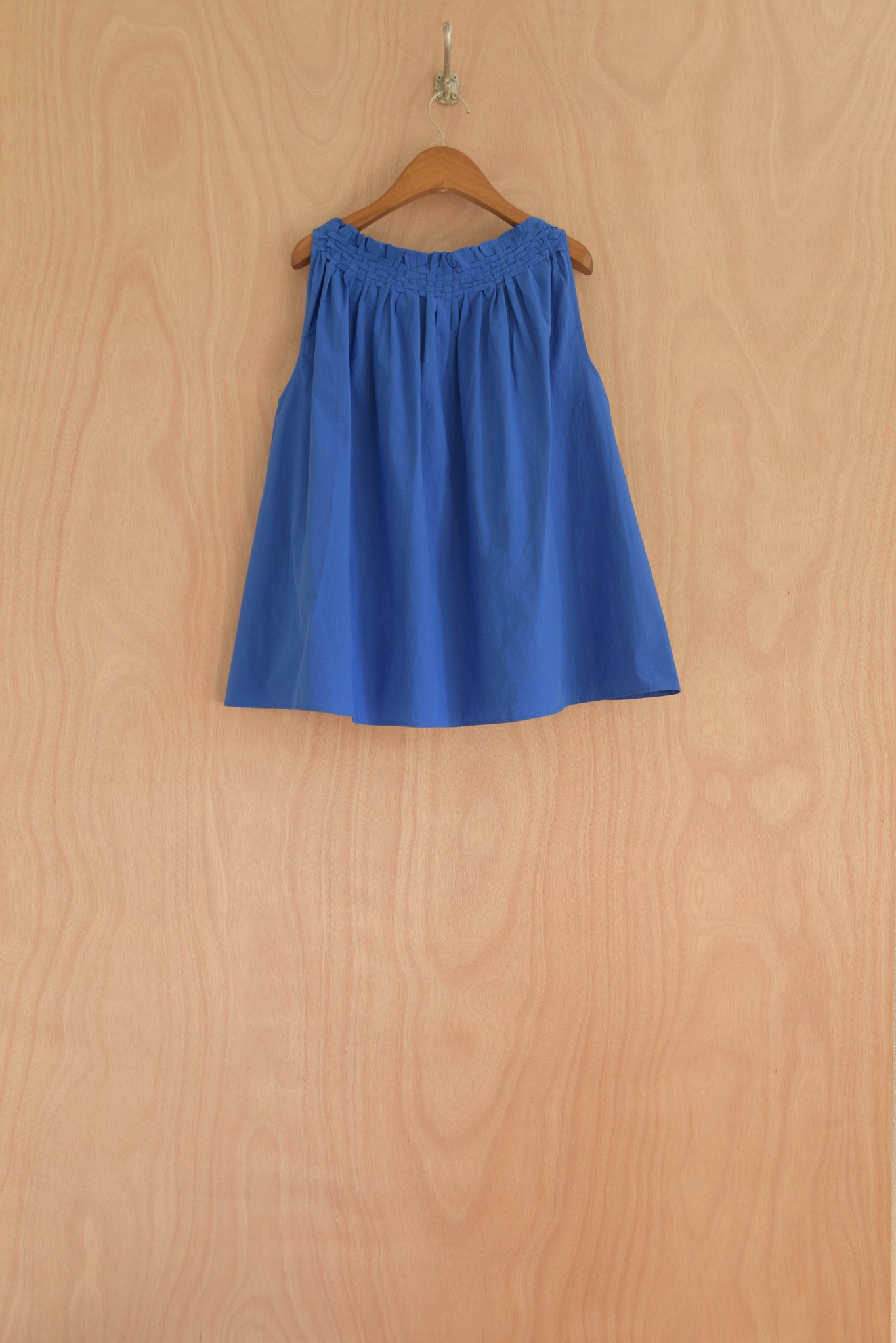 Back view of the Olga Top in blue, highlighting the relaxed drape and open silhouette.