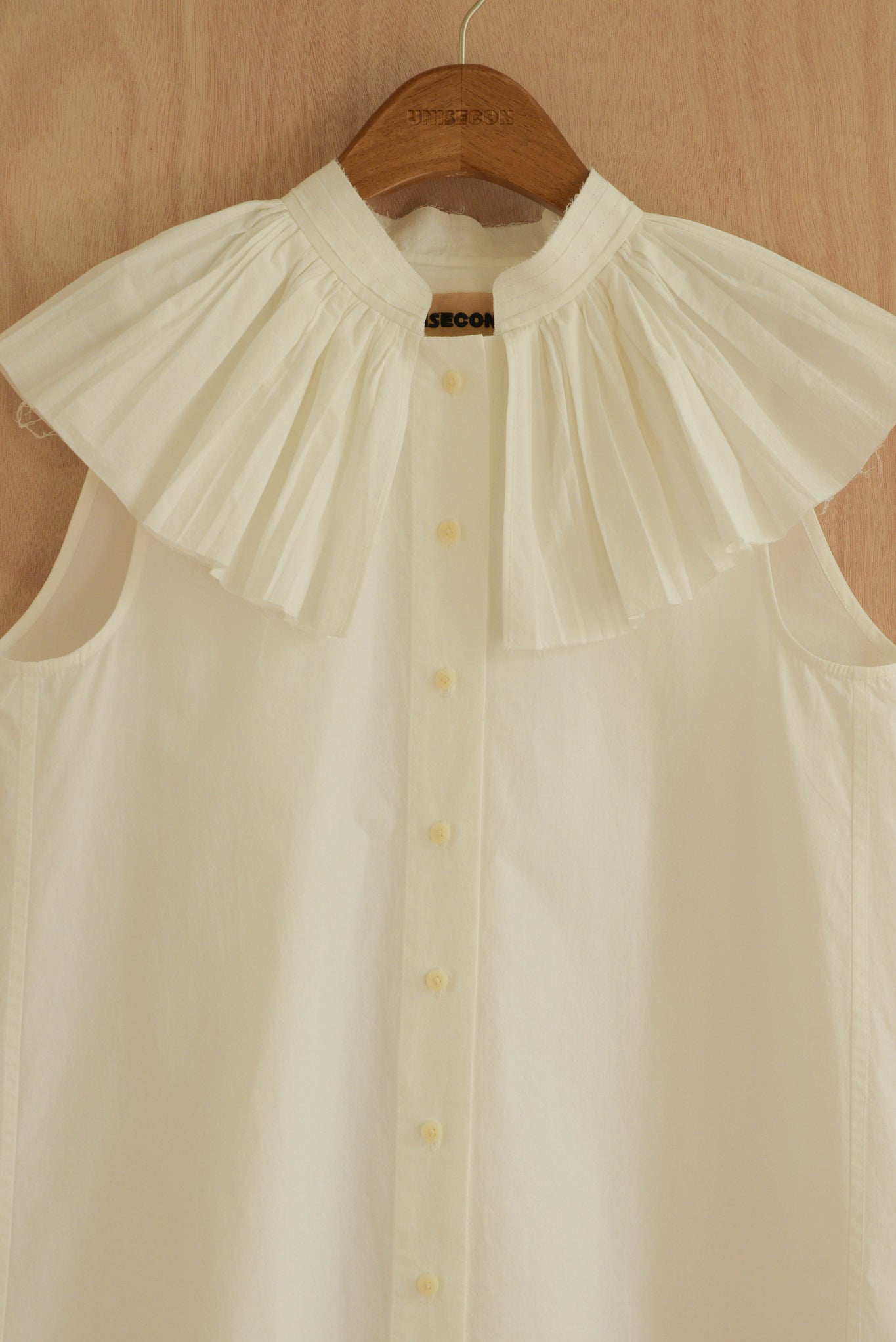 Close-up of Rea Top in white, highlighting the pleated collar.