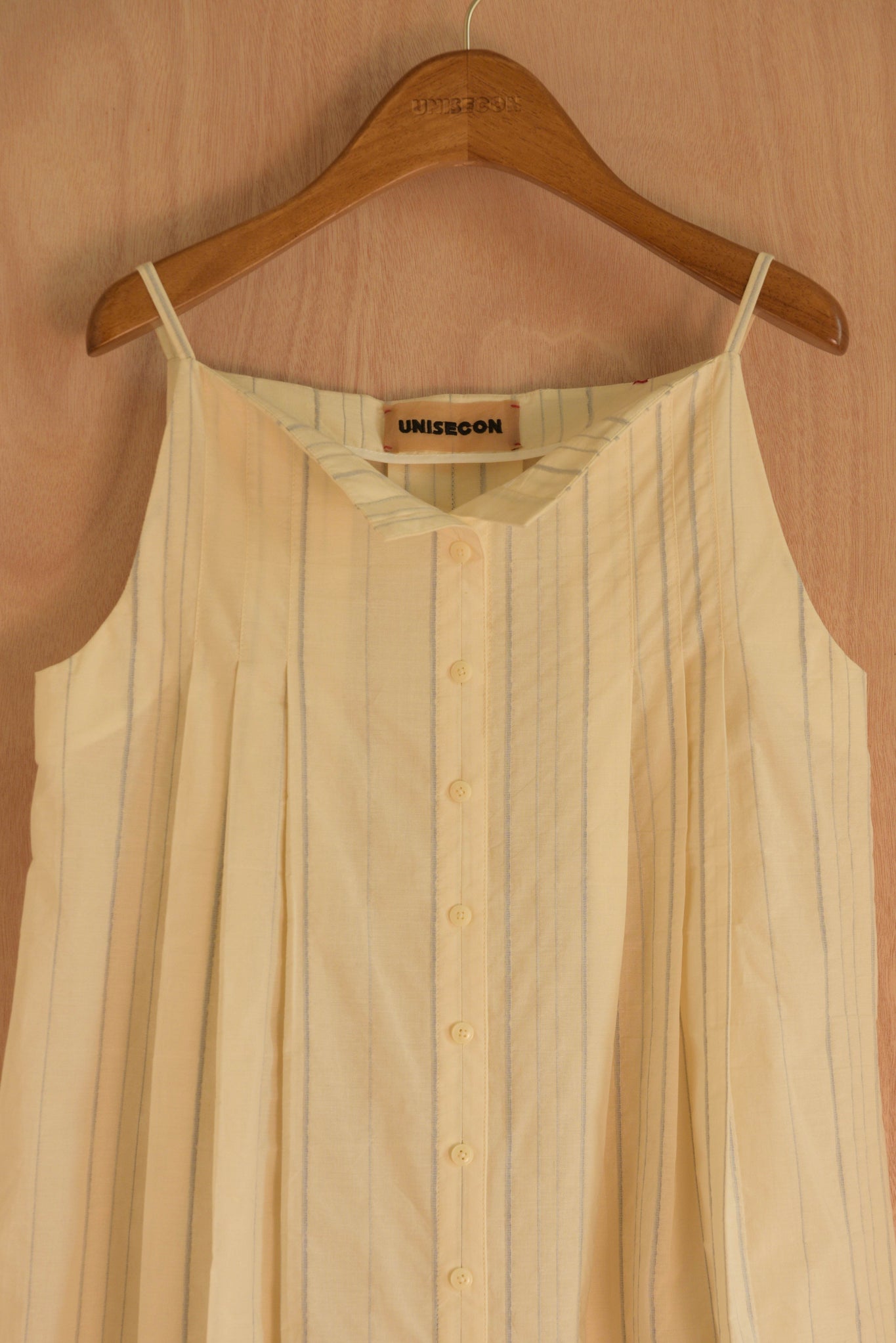  Close-up of the fabric and pleats on the Sharrin Top in cream cotton.